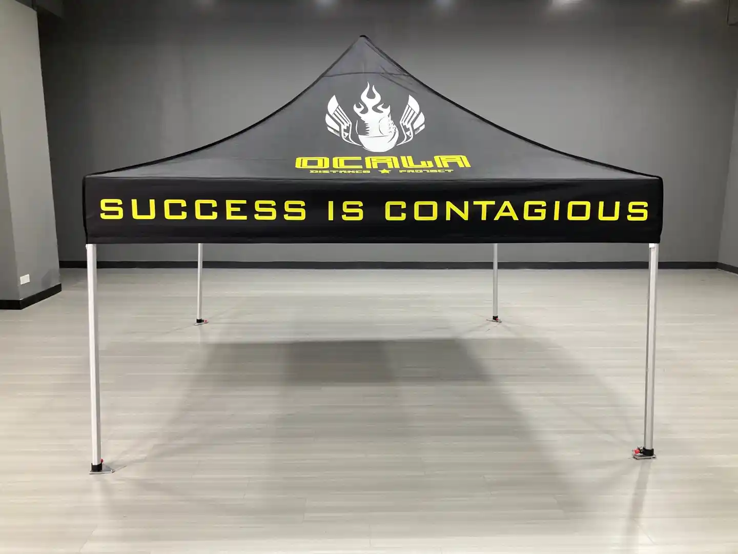 OCALA Distance Project 10x10 custom tent — yellow 'Success Is Contagious' branding on black canopy